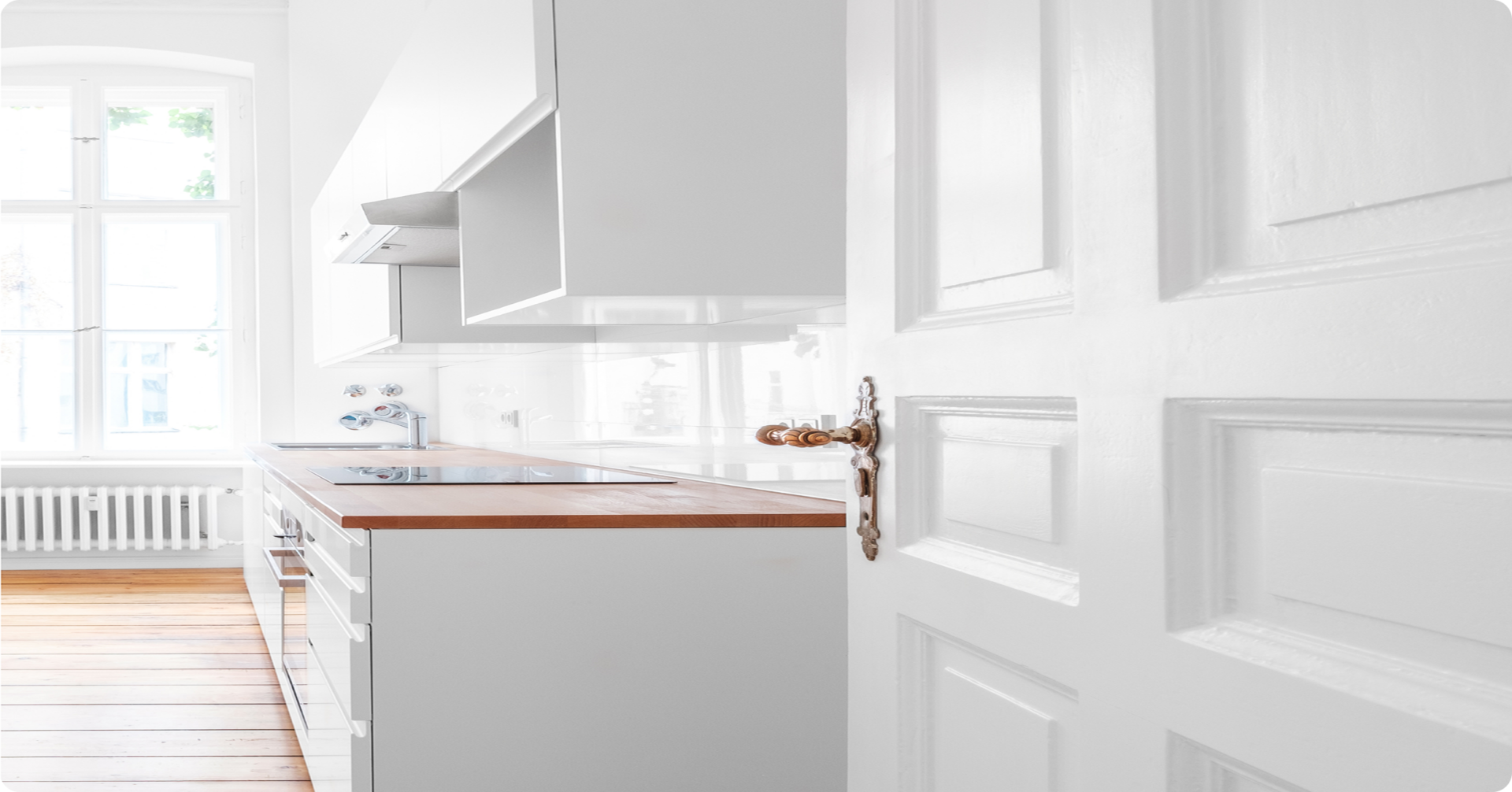 Minimalist white kitchen with wooden countertops.